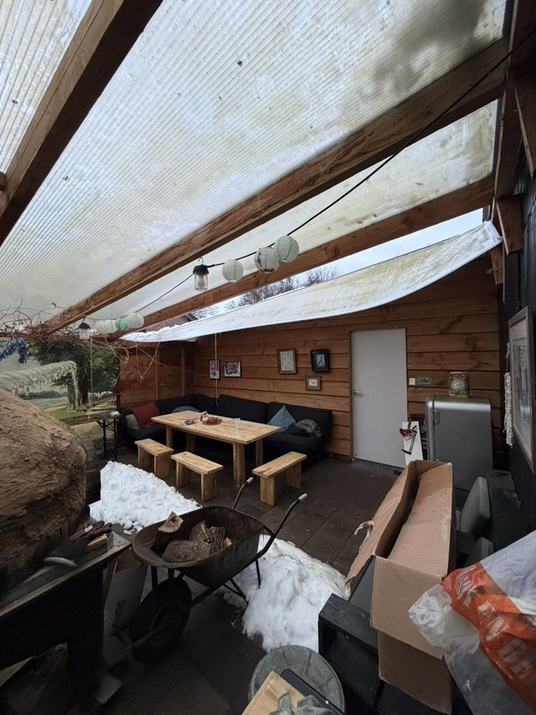 Door teveel sneeuw igestort dak bij de pizzoven met op de grond de sneeuw die op het dak lag
