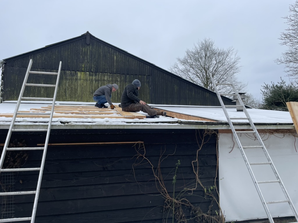 Hans en Ianus op het dak terwijl ze de ingestorte plaat aan het terugplaatsen zijn